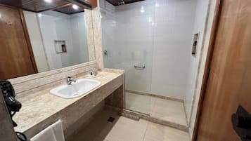 Un baño moderno con lavamanos doble, cabina de ducha con mampara de vidrio y un espejo grande.