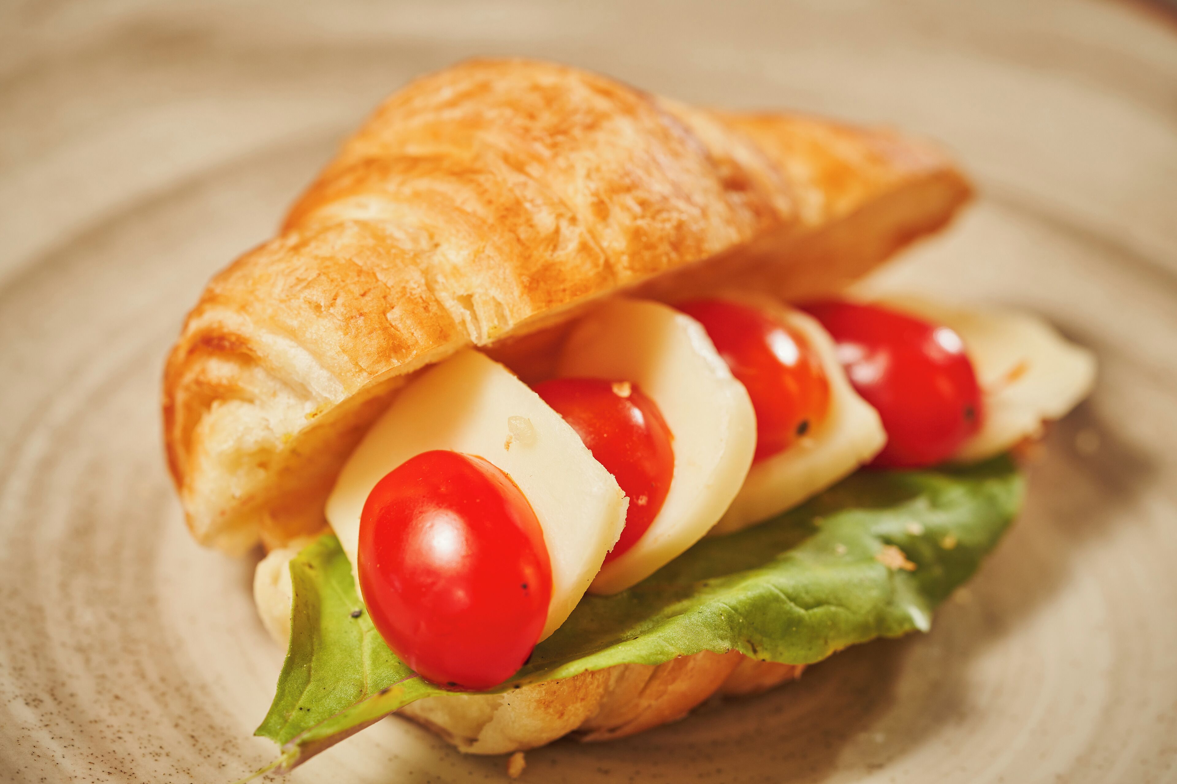 Un sándwich con un pan rústico, queso, tomates y lechuga.