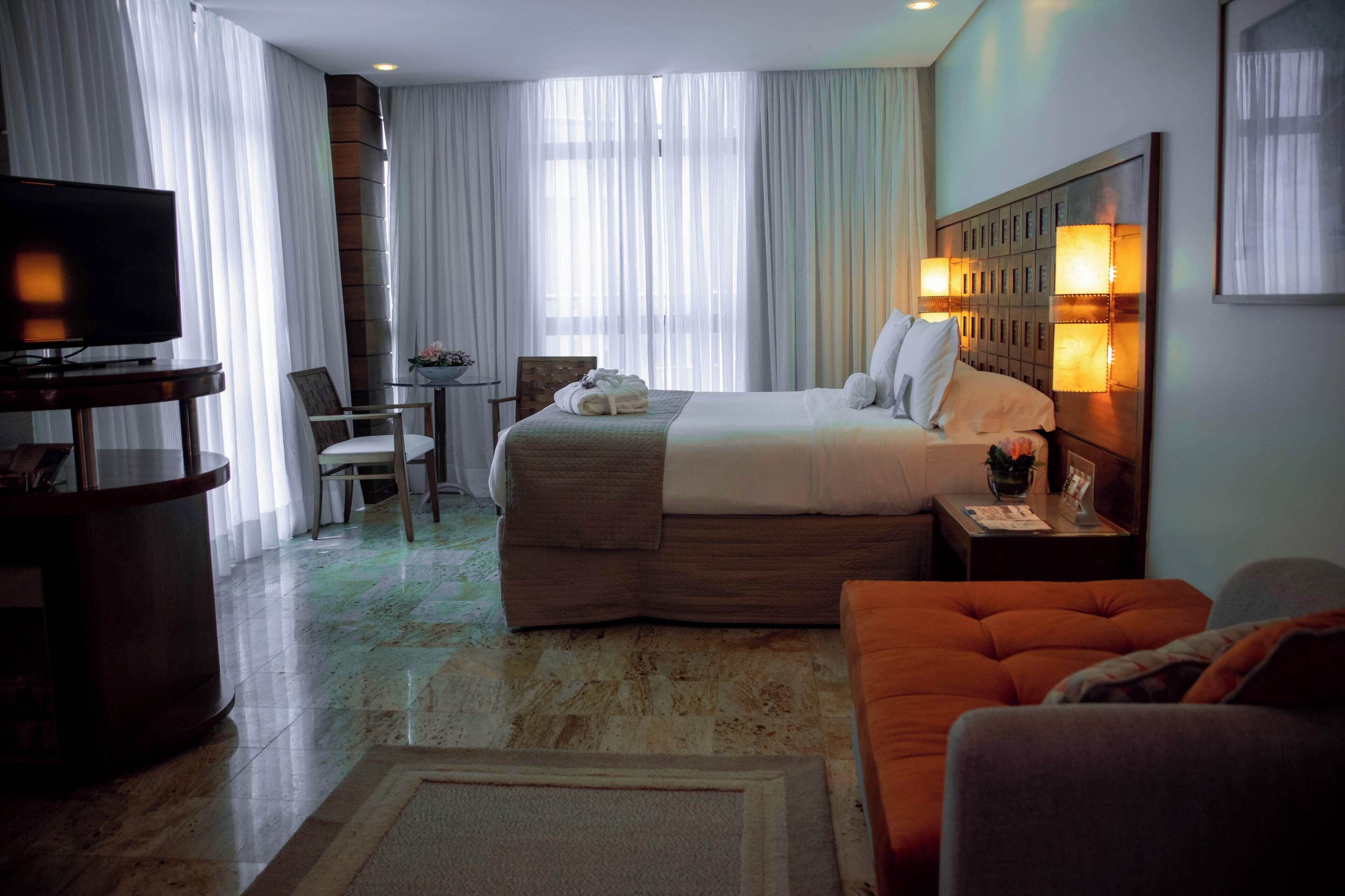 Una habitación de hotel con una cama grande, un televisor, un escritorio con una silla y un sofá.