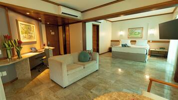 Una habitación de hotel con sofá, cama, escritorio y televisor.
