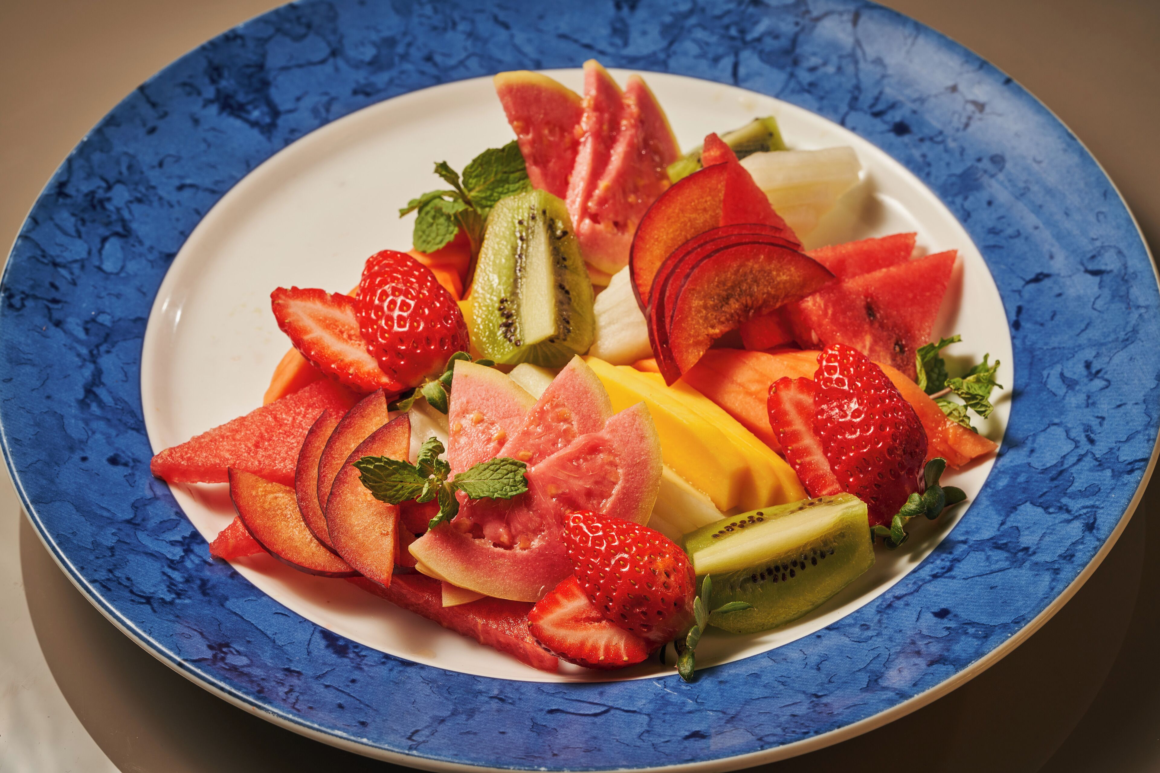 Un plato con frutas cortadas, incluyendo fresas, kiwi, sandía y mango.