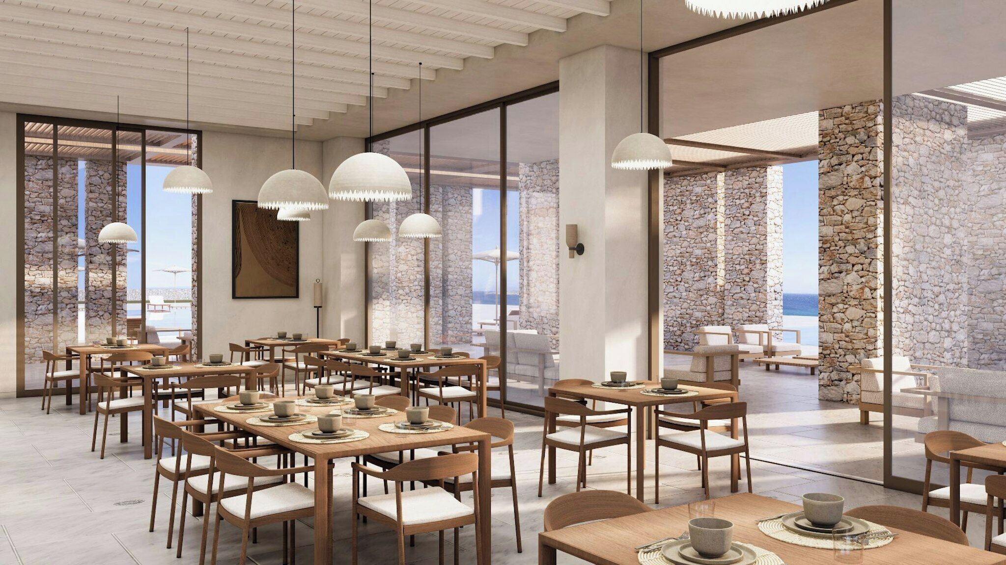 Un comedor amplio con varias mesas y sillas, ventanas grandes que ofrecen vista al mar, e iluminación colgante moderna.