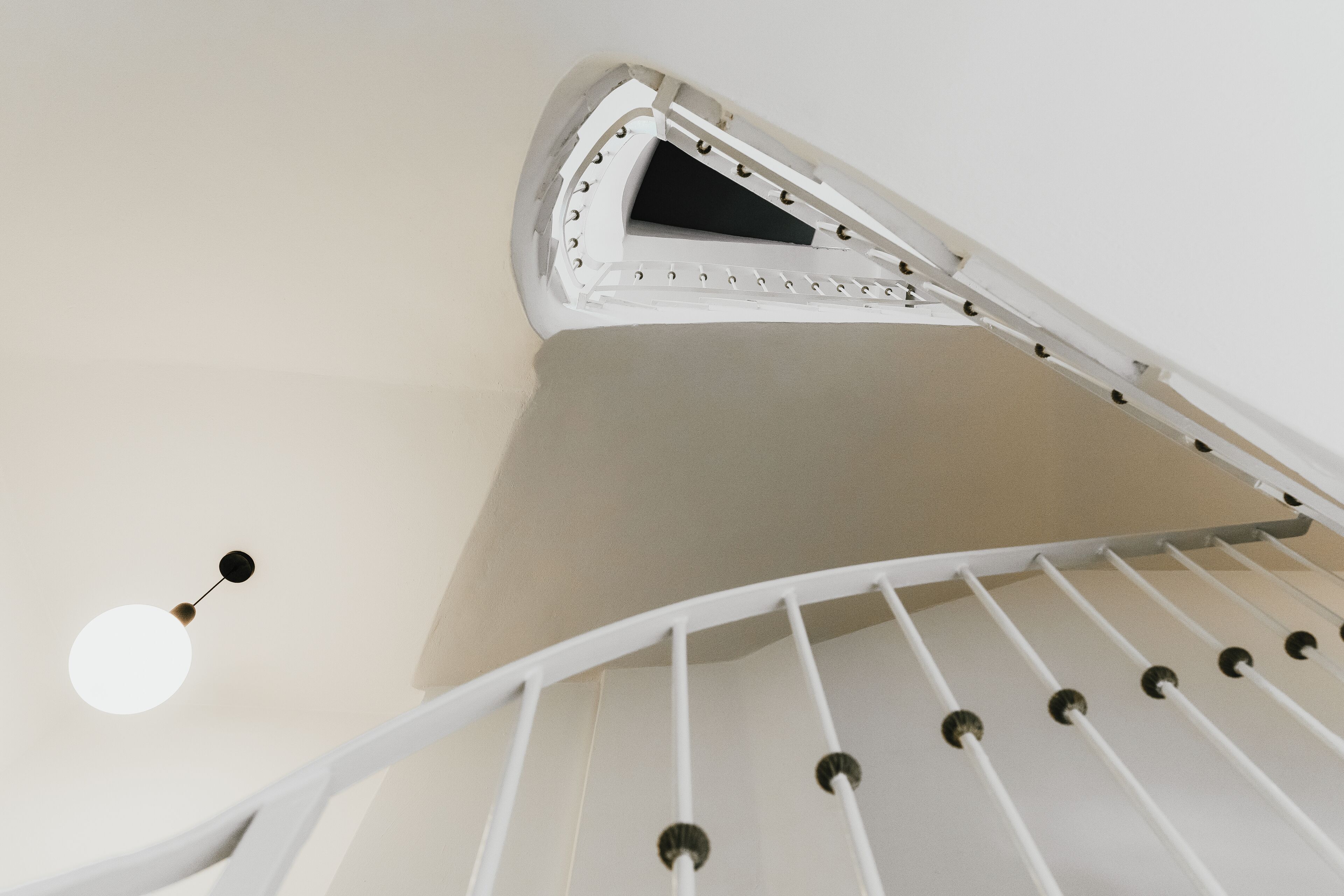 A white spiral staircase with a ceiling light fixture.