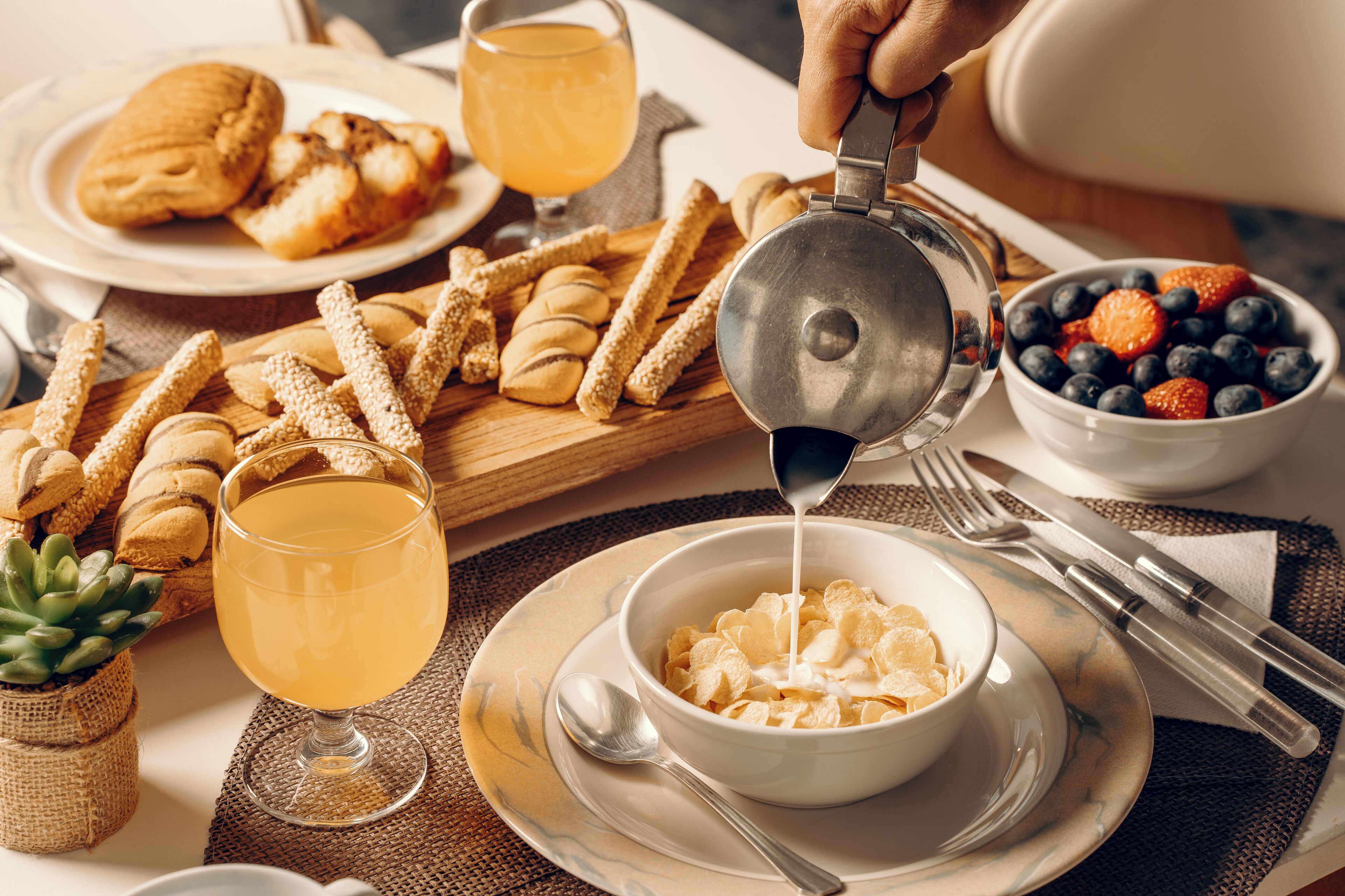 A breakfast setting with cereal, toast, and a bowl of fruit.