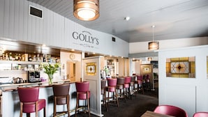 A bar area with a sign reading "GOLLY'S" and multiple bar stools. - Carna Bay Hotel (Carna)