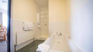 A bathroom with a bathtub, a shower area, and a radiator.
