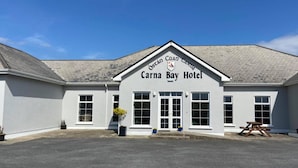 A building labeled "Carna Bay Hotel" with a clear entrance, windows, and a picnic table outside. - Carna Bay Hotel (Carna)
