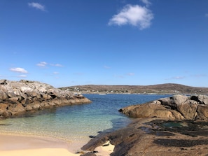 A coastal landscape with clear blue waters, rocky shorelines, and distant hills. - Carna Bay Hotel (Carna)