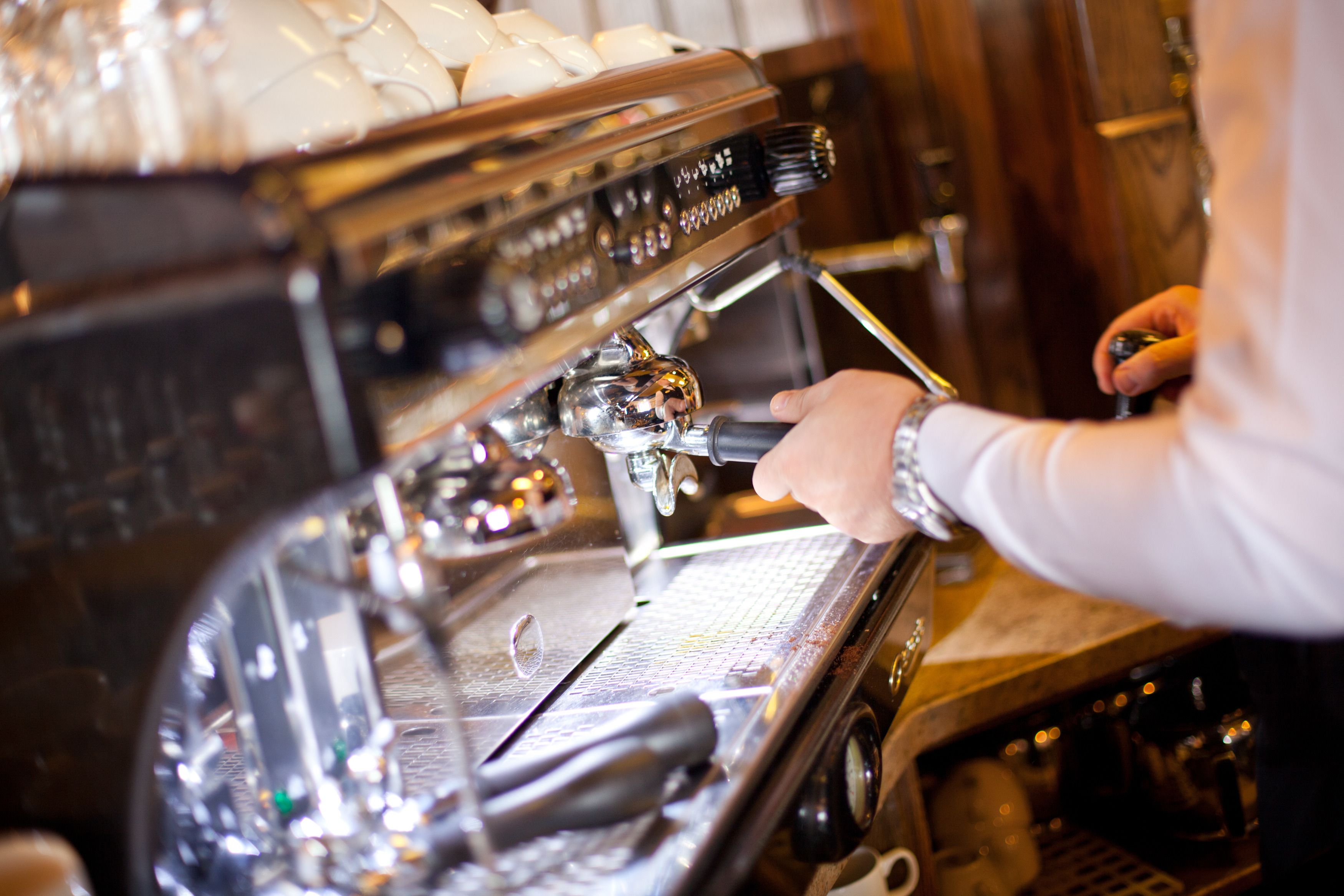 Eine Nahaufnahme einer Kaffeemaschine, die von einer Hand bedient wird.