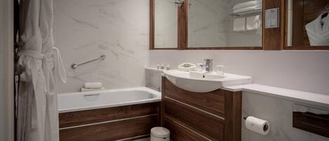 A modern bathroom with a marble floor, a bathtub, a vanity with a sink, and a mirror above the vanity.