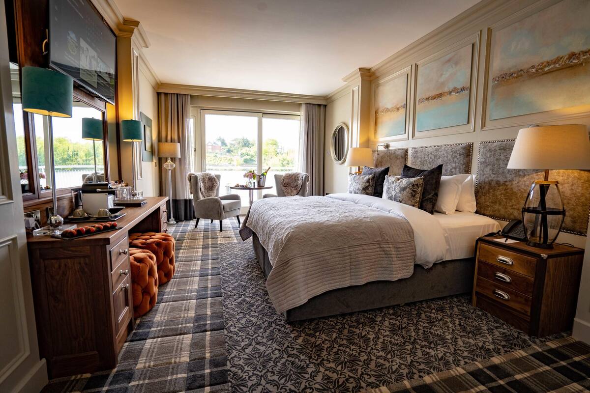 Une chambre d’hôtel avec un grand lit, un bureau doté d’un téléviseur à écran plat, deux chaises, une petite table et une vue sur l’extérieur.