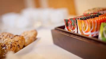 A buffet table with various food items, including pastries and a tray of colorful fruit cups.