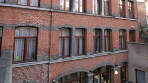 Een meerhoog gebouw van baksteen met gebogen ramen en een klok op de gevel.
