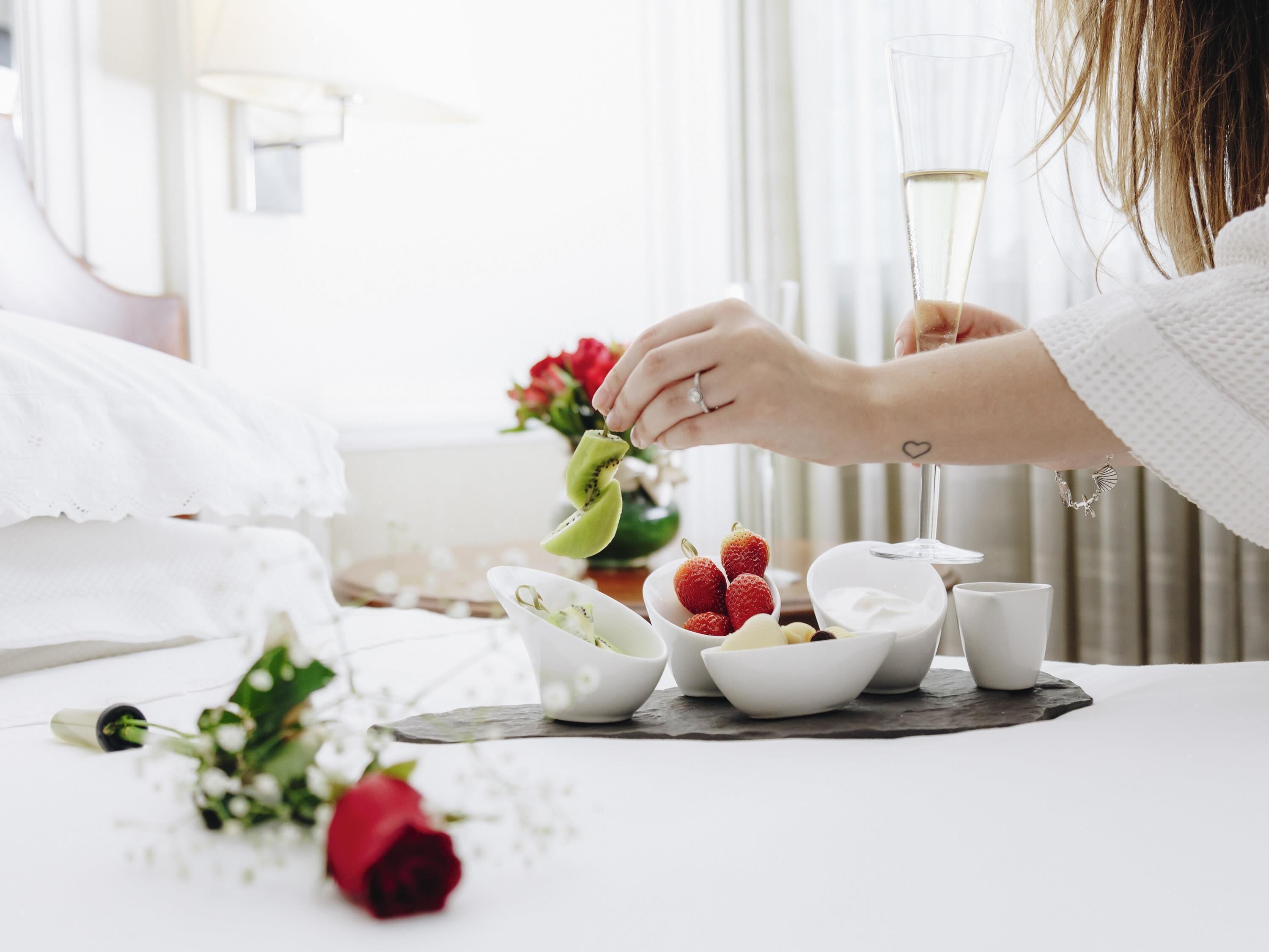 A neatly arranged breakfast setting with a white table, a bowl of strawberries, a bowl of yogurt, and a glass of white beverage.