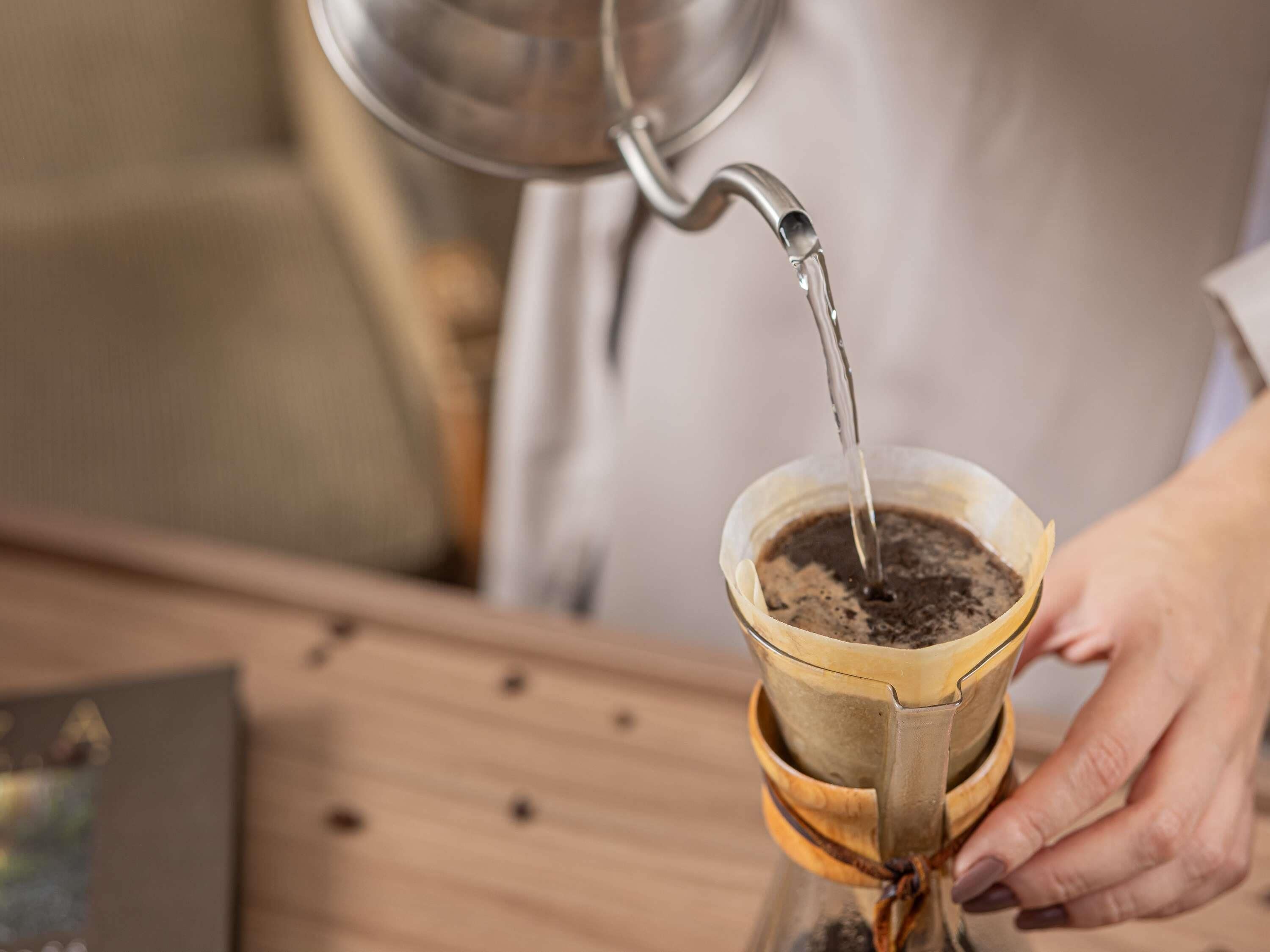 A person pouring water into a coffee dripper over coffee grounds.