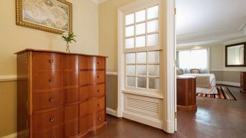 A room with a wooden dresser, a large window with frosted glass, and a bed with a striped rug.