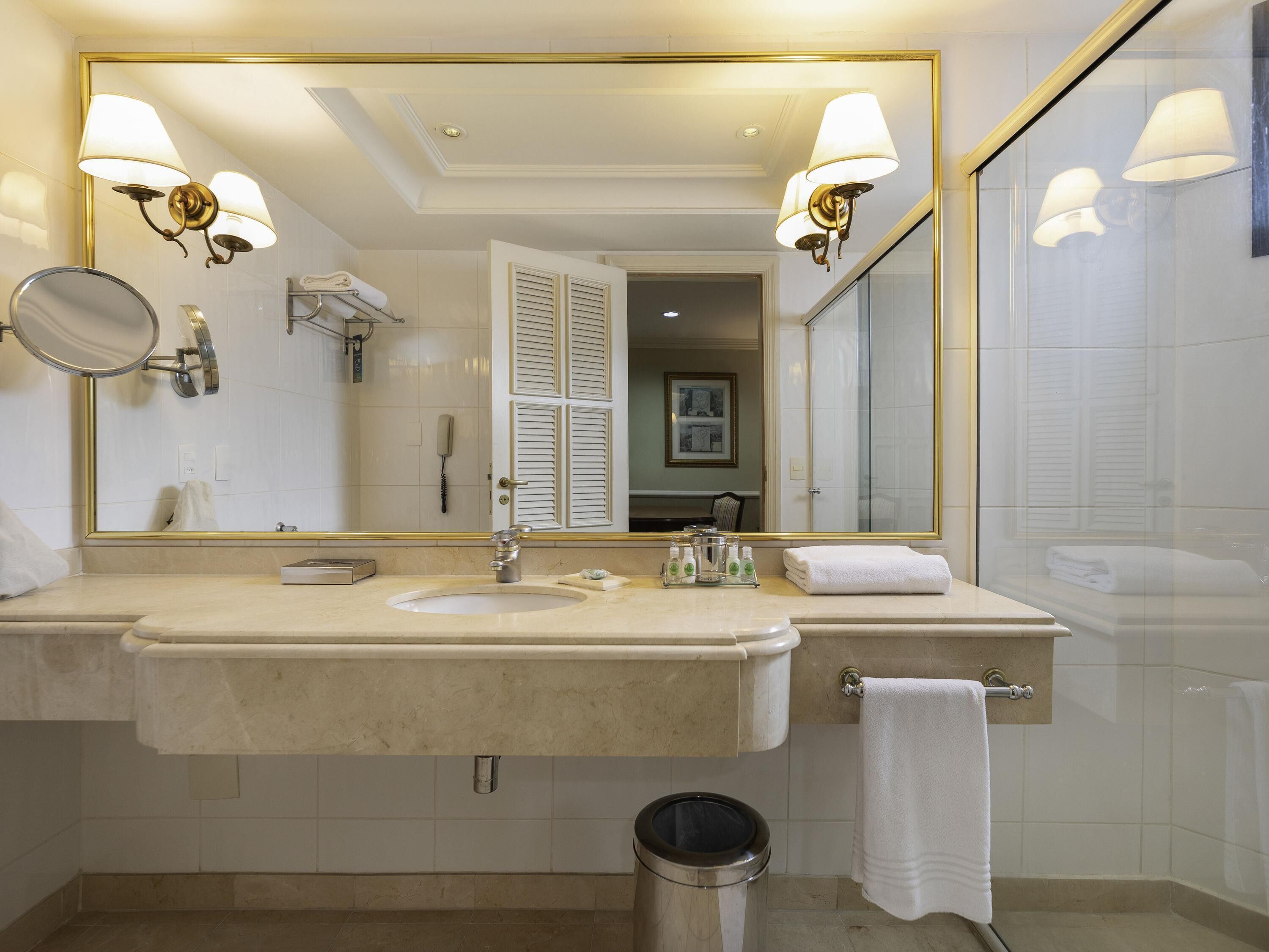 Une salle de bain d’hôtel avec deux lavabos, un miroir, une poubelle et un porte-serviettes.
