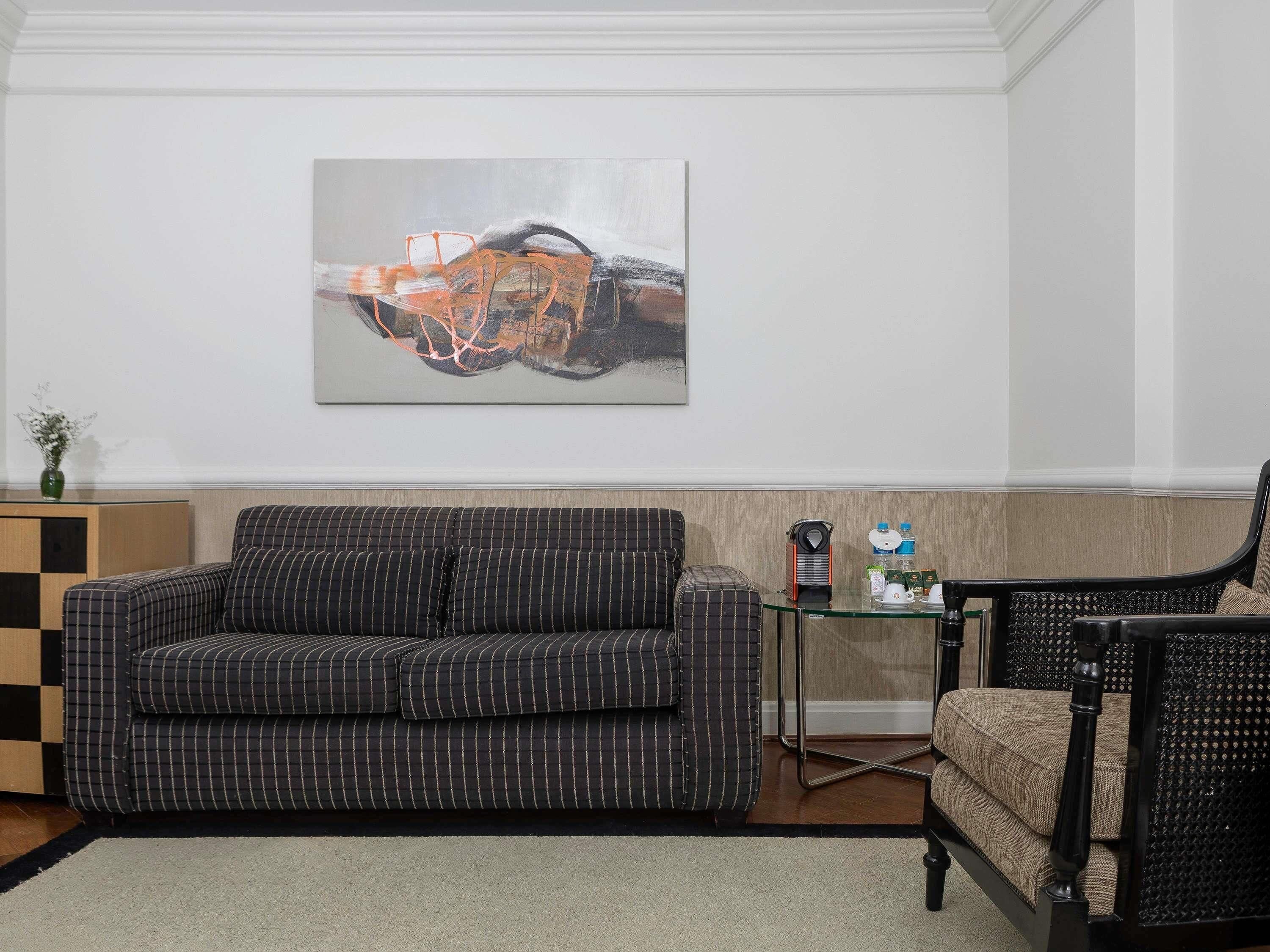 A living room with a sofa, a coffee table, a chair, and a painting on the wall.