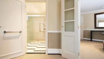Habitación de hotel con cabina de ducha de vidrio, suelo a cuadros y puerta con paneles de vidrio esmerilado.