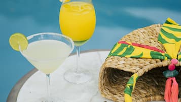 A table with two drinks, a straw hat, and sunglasses.