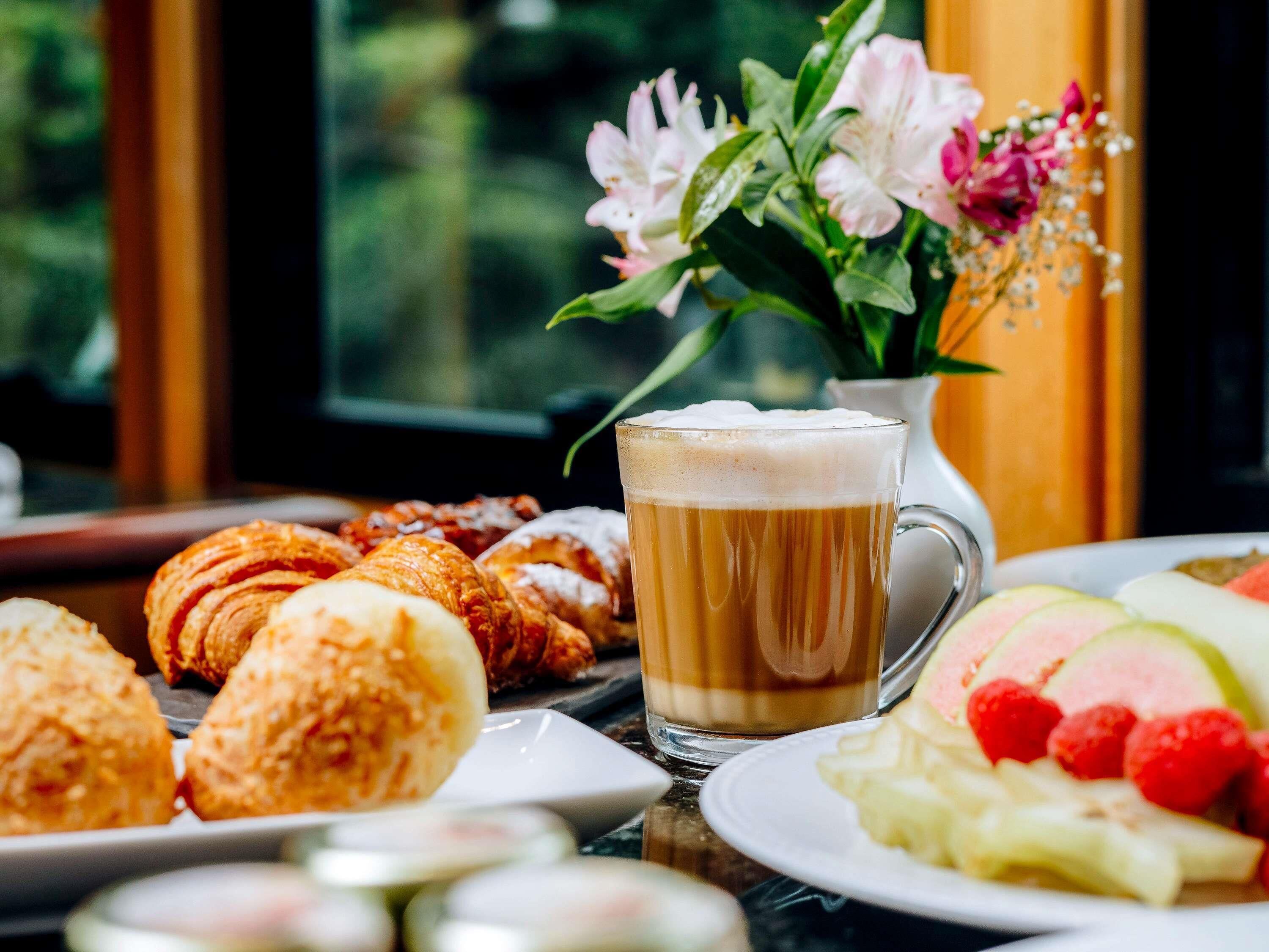 A table with pastries, a mug of coffee, and a plate of fruit.