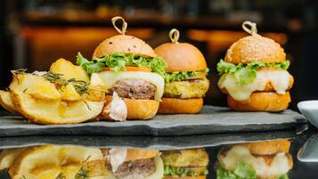 Three burgers with fries and a side of chips.