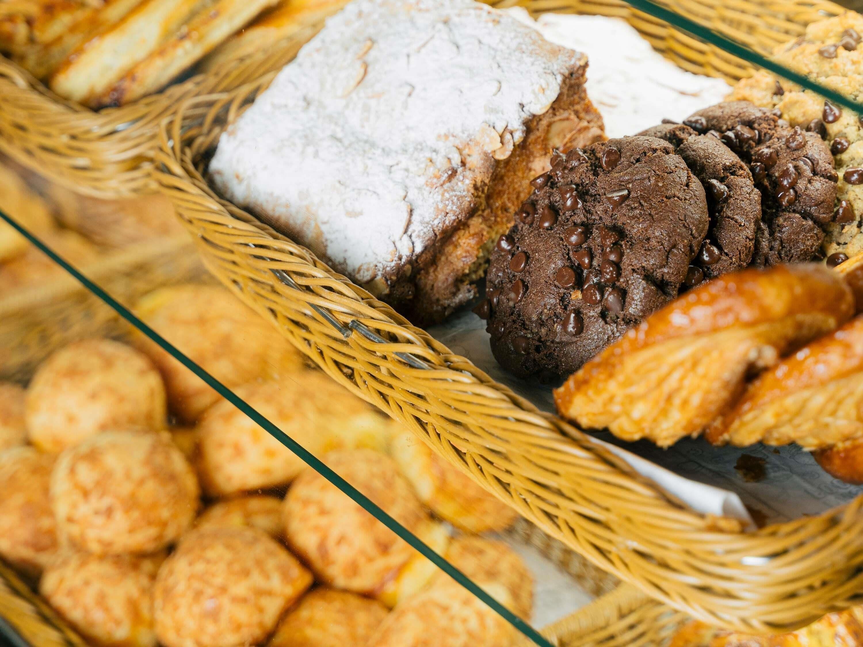 A variety of baked goods including bread, cookies, and pastries displayed in a wicker basket.