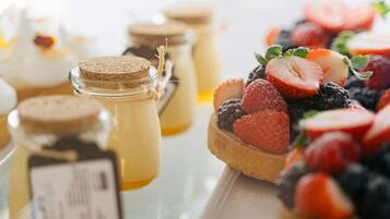 A dessert table with various pastries and jars of honey.