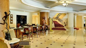 Un vestíbulo espacioso con una imponente escalera, muebles elegantes y una recepción.