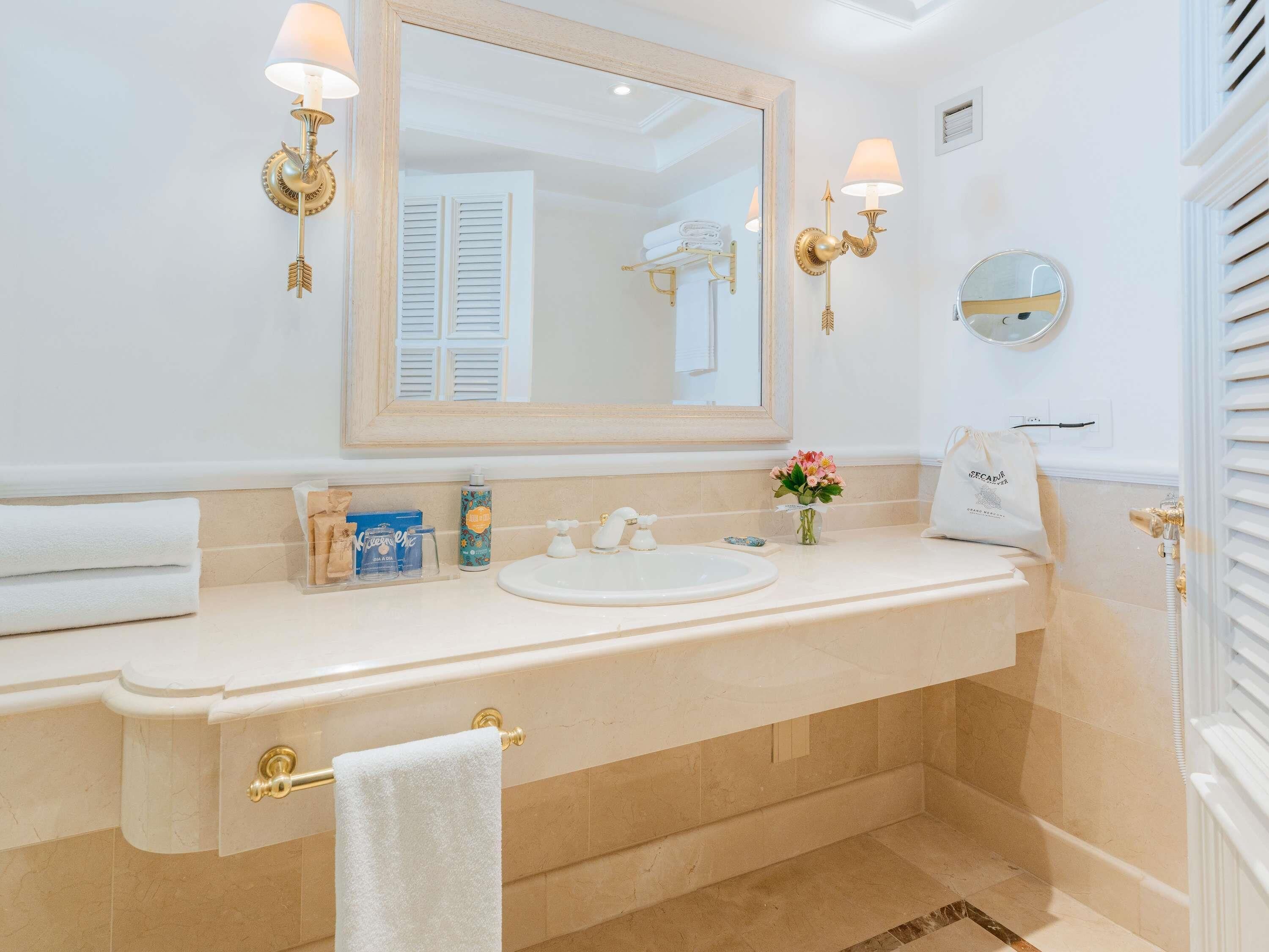 A bathroom with a large mirror, a sink, a towel rack, and a shower area.