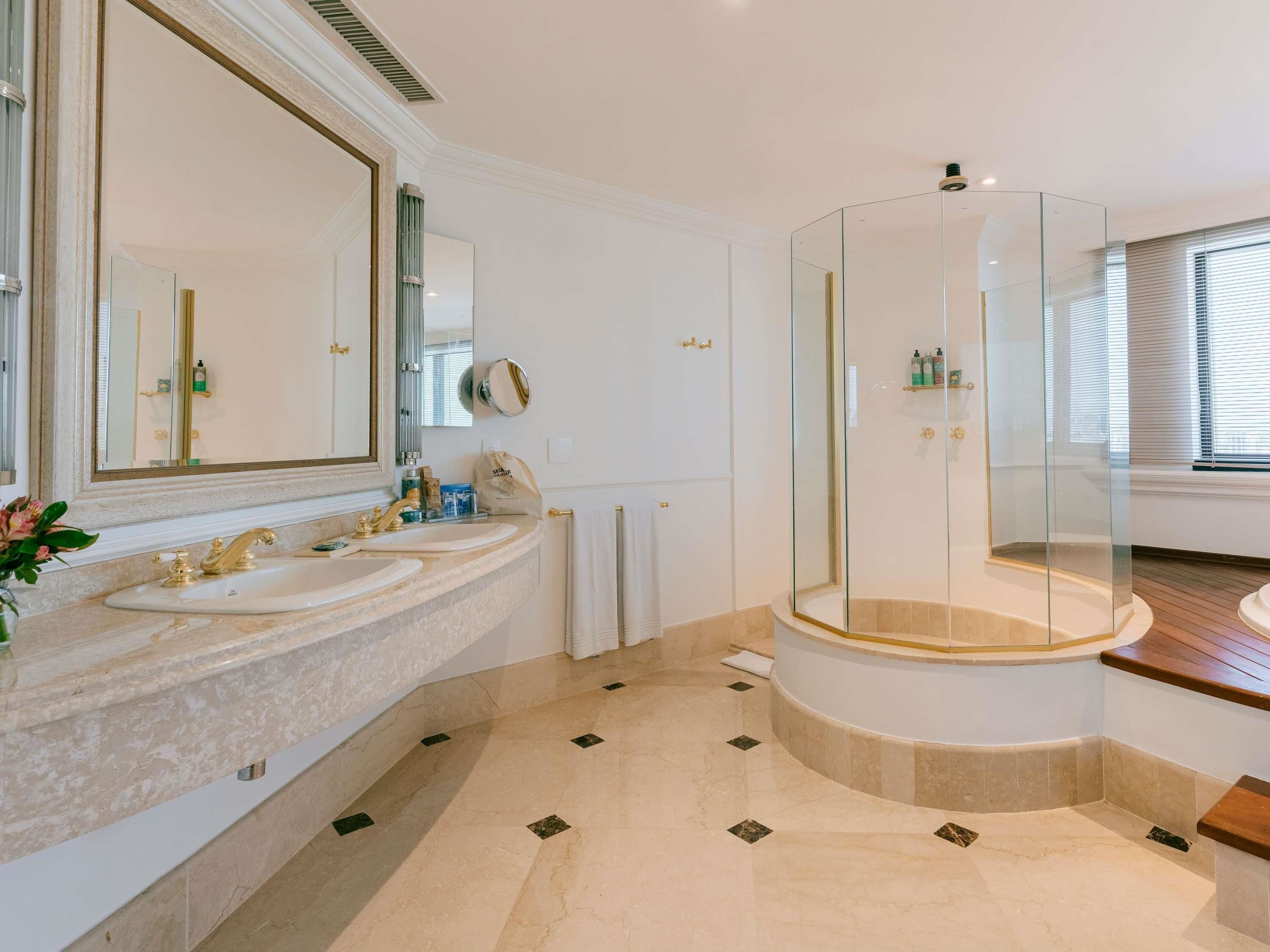 Un bagno moderno con due lavandini, uno specchio grande e una cabina doccia in vetro.