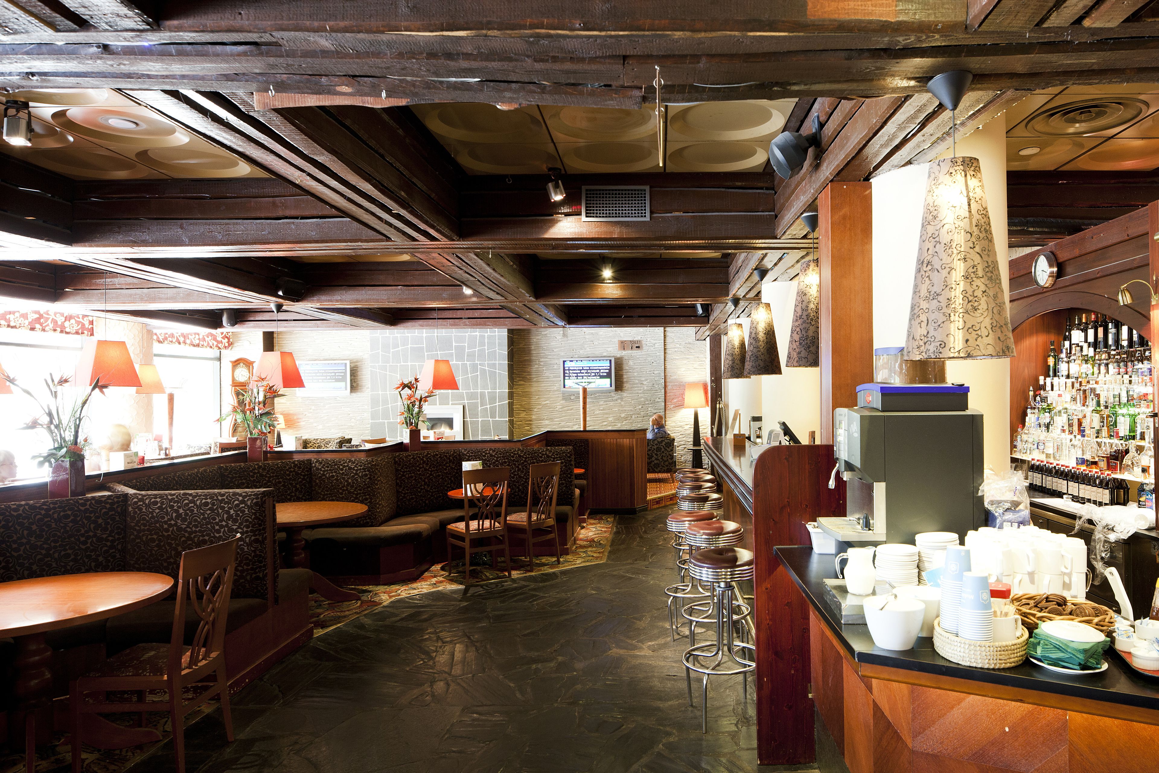 A restaurant with wooden beams, a bar area with stools, and a seating area with tables and chairs.