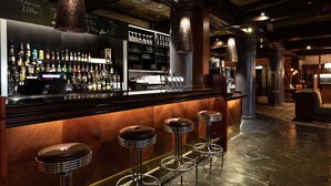 Un espace bar doté d’un sol en marbre poli, d’un comptoir avec une caisse enregistreuse et de trois tabourets.