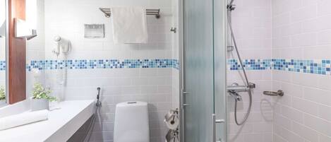 A bathroom with a toilet, a shower, a sink, and a mirror.
