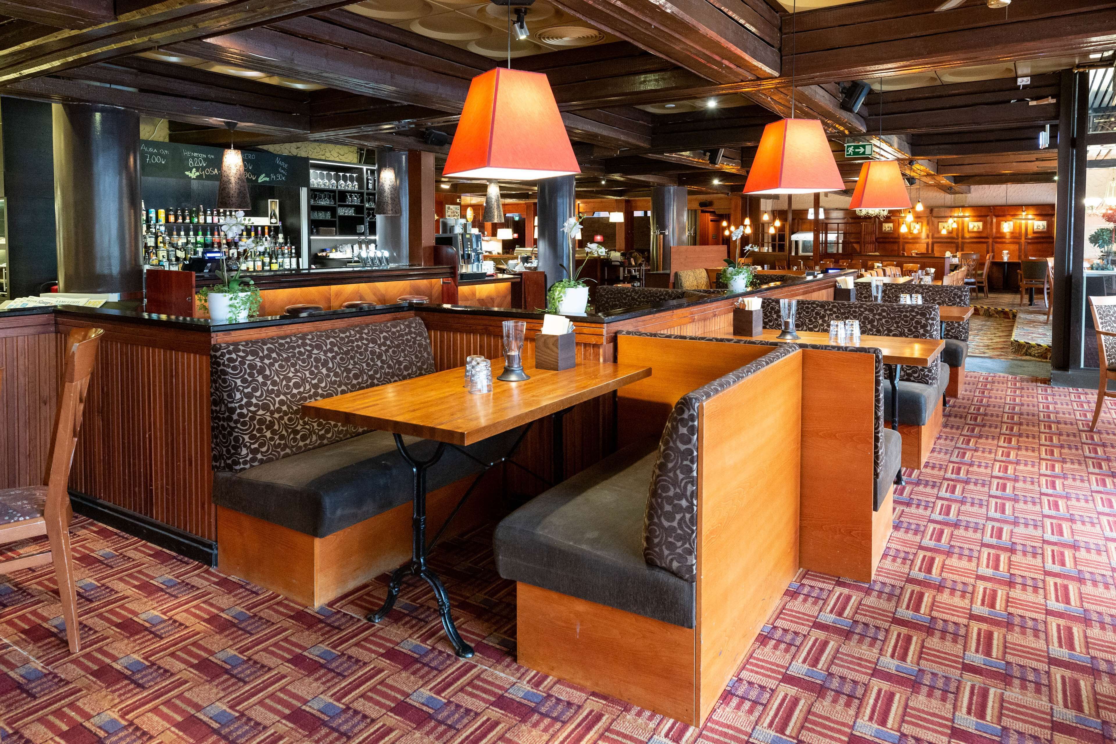 A restaurant with booths and tables, a bar area, and patterned carpet flooring.