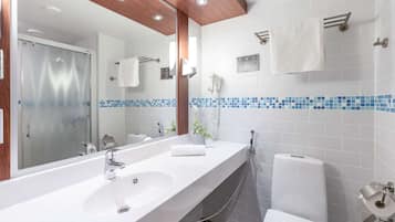 A modern bathroom with a large mirror, two sinks, a shower, and a toilet.