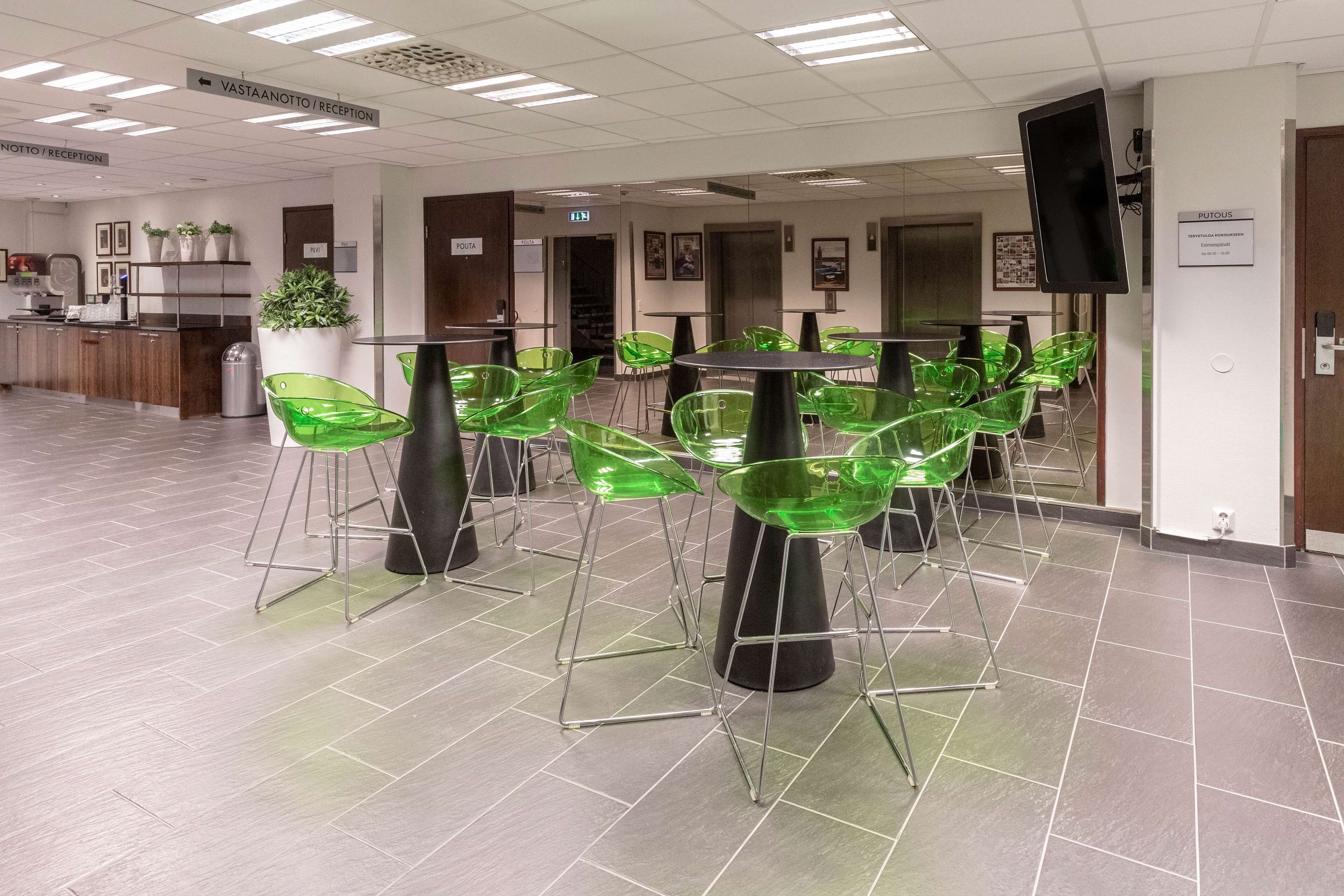 A reception area with a reception desk, green chairs, and a sign indicating the direction to the reception.