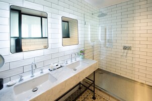 Un bagno moderno con due lavandini, uno specchio grande e un box doccia in vetro.