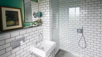 Un baño moderno con azulejos blancos tipo metro, un lavamanos blanco, un espejo y una zona de ducha.