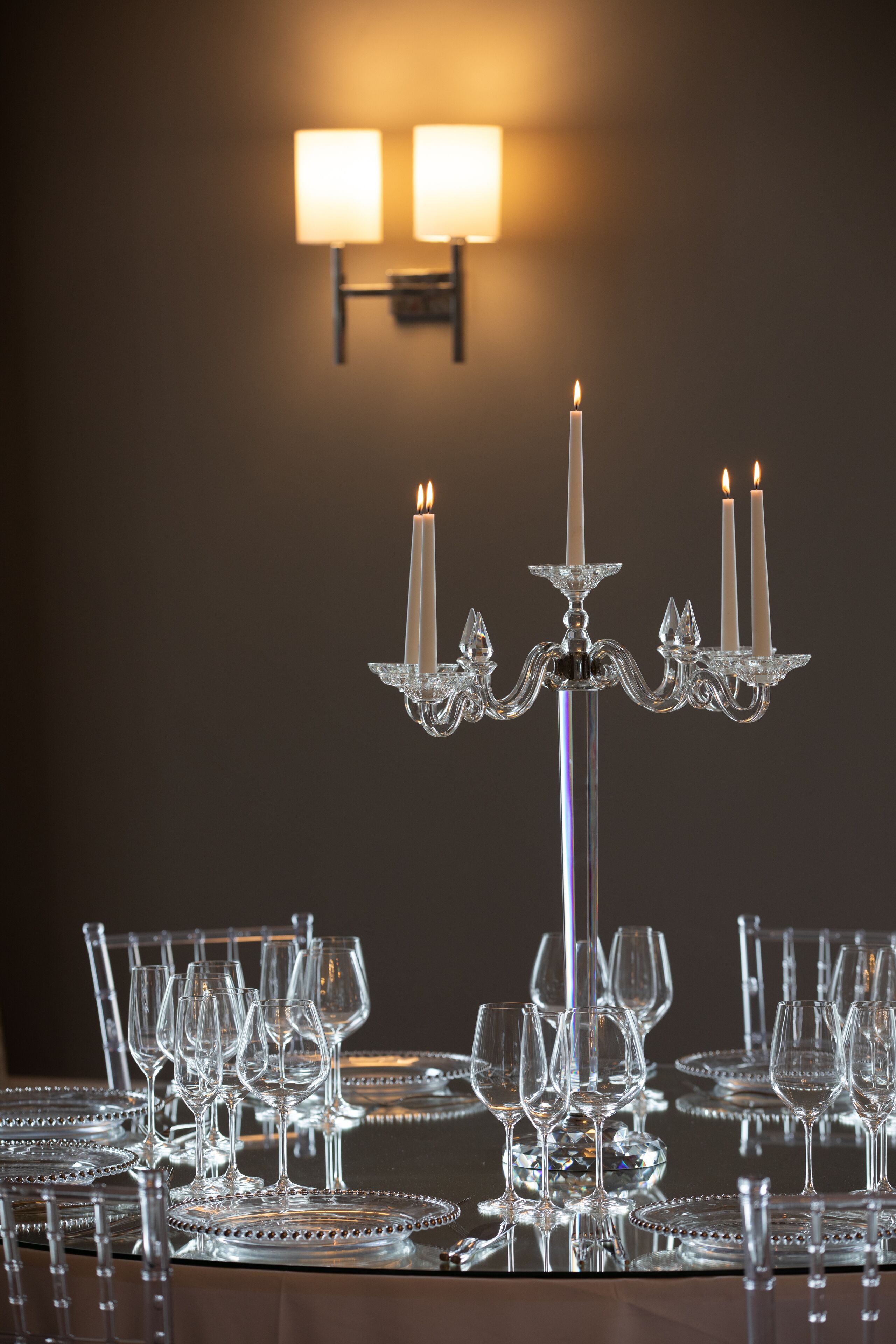 A table set with multiple wine glasses and a crystal candelabra with lit candles.