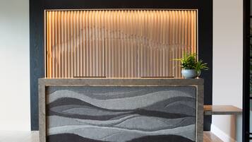 A reception area with a modern design, featuring a vertical wooden panel and a textured wall panel.