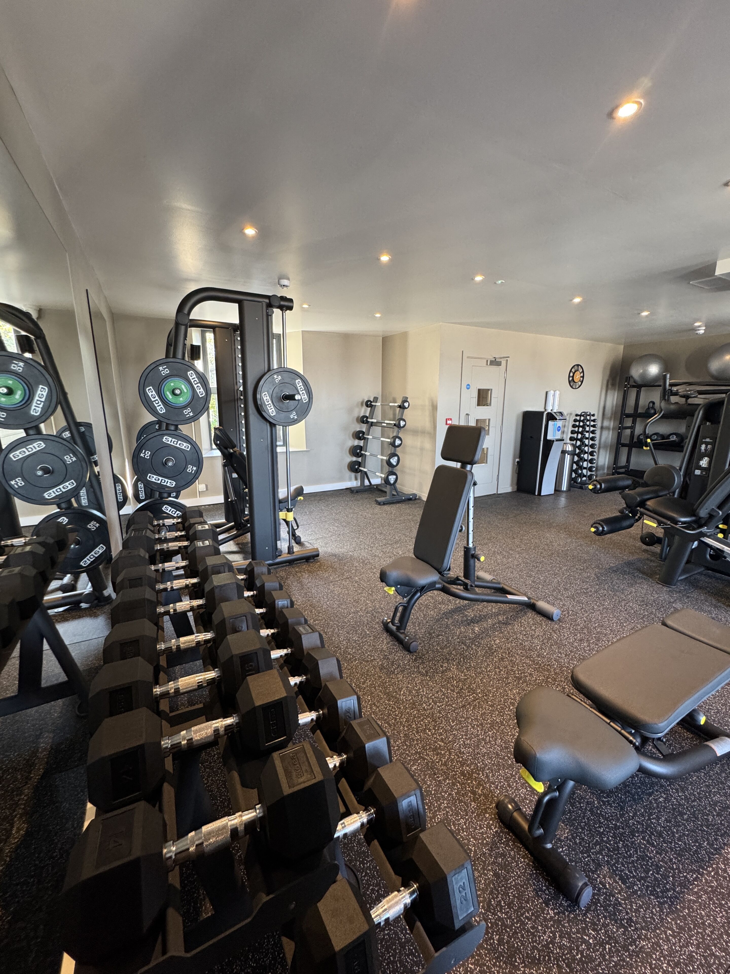 A gym with various exercise equipment, including dumbbells, weight machines, and a bench.