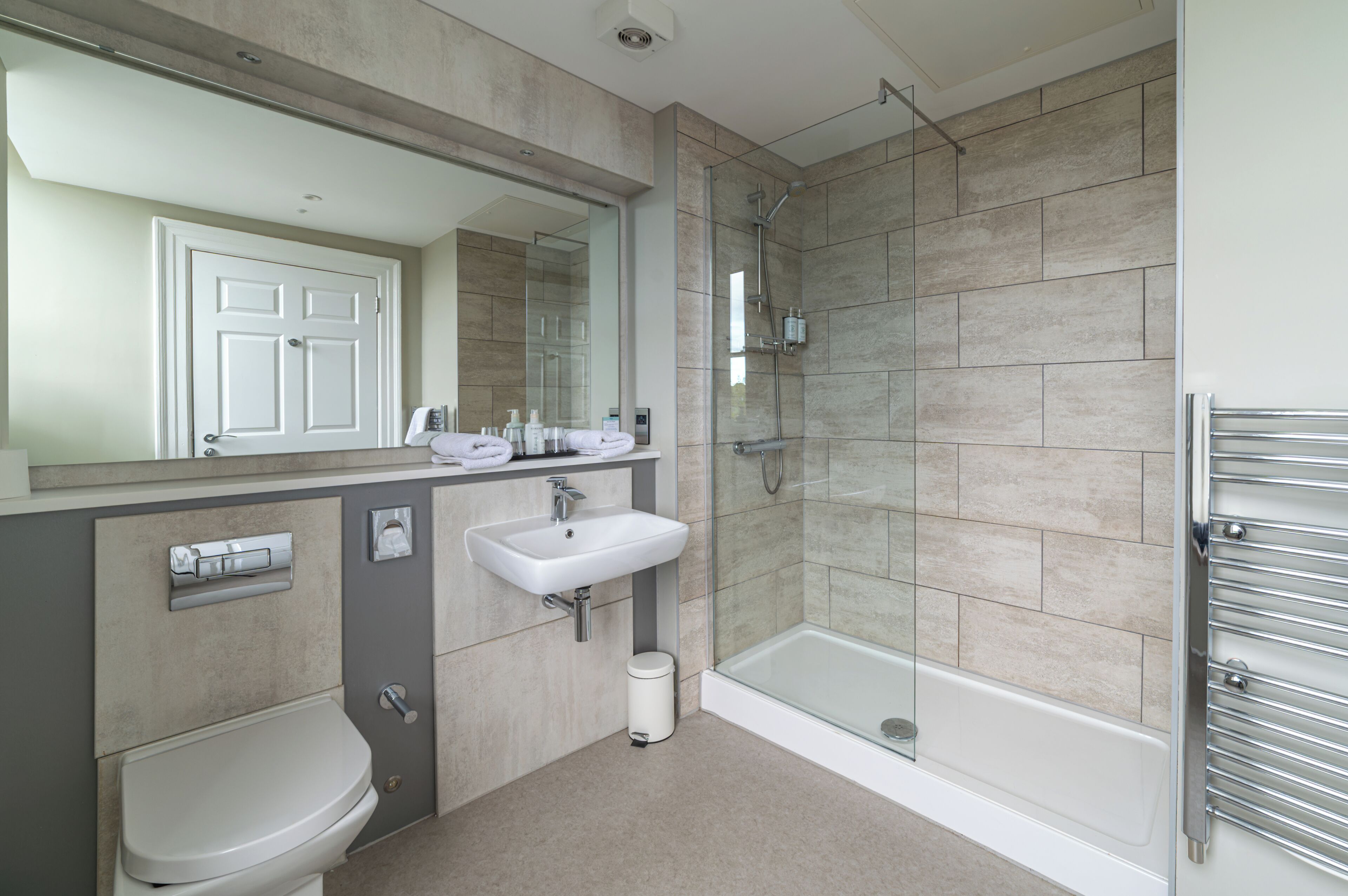A modern bathroom with a toilet, sink, and glass-enclosed shower.