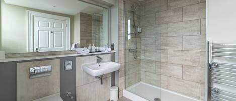 A modern bathroom with a toilet, sink, and glass-enclosed shower.