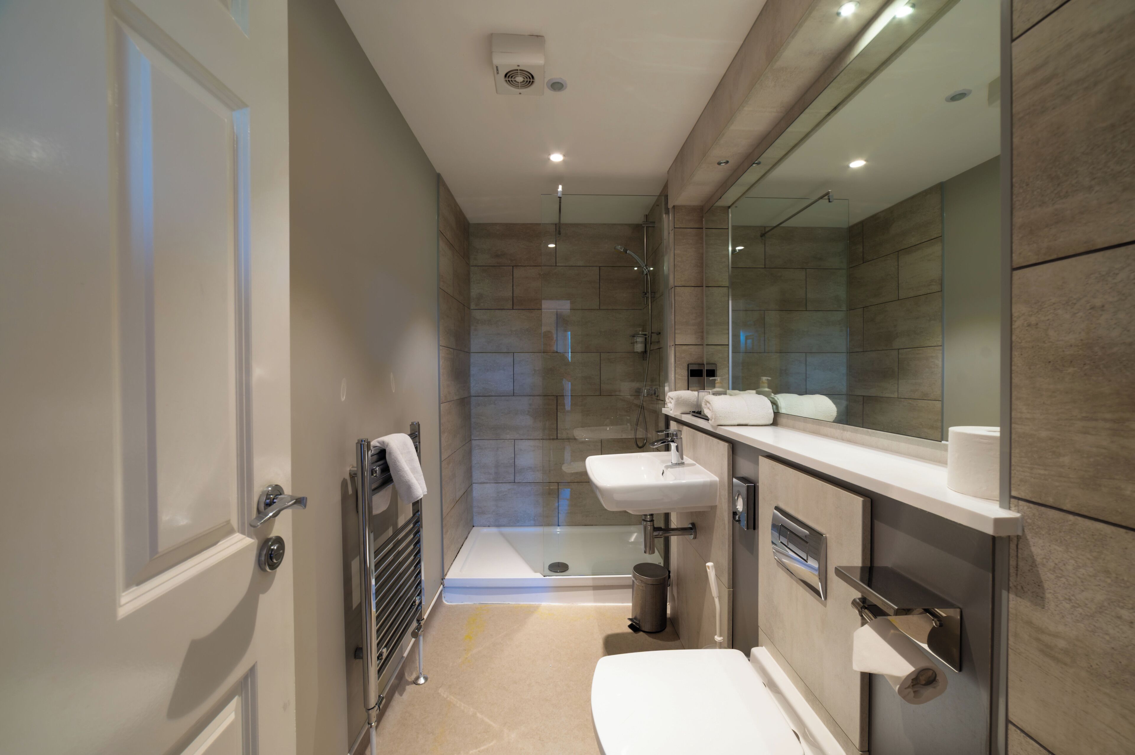 A modern bathroom with a glass shower enclosure, a white sink, and a toilet.