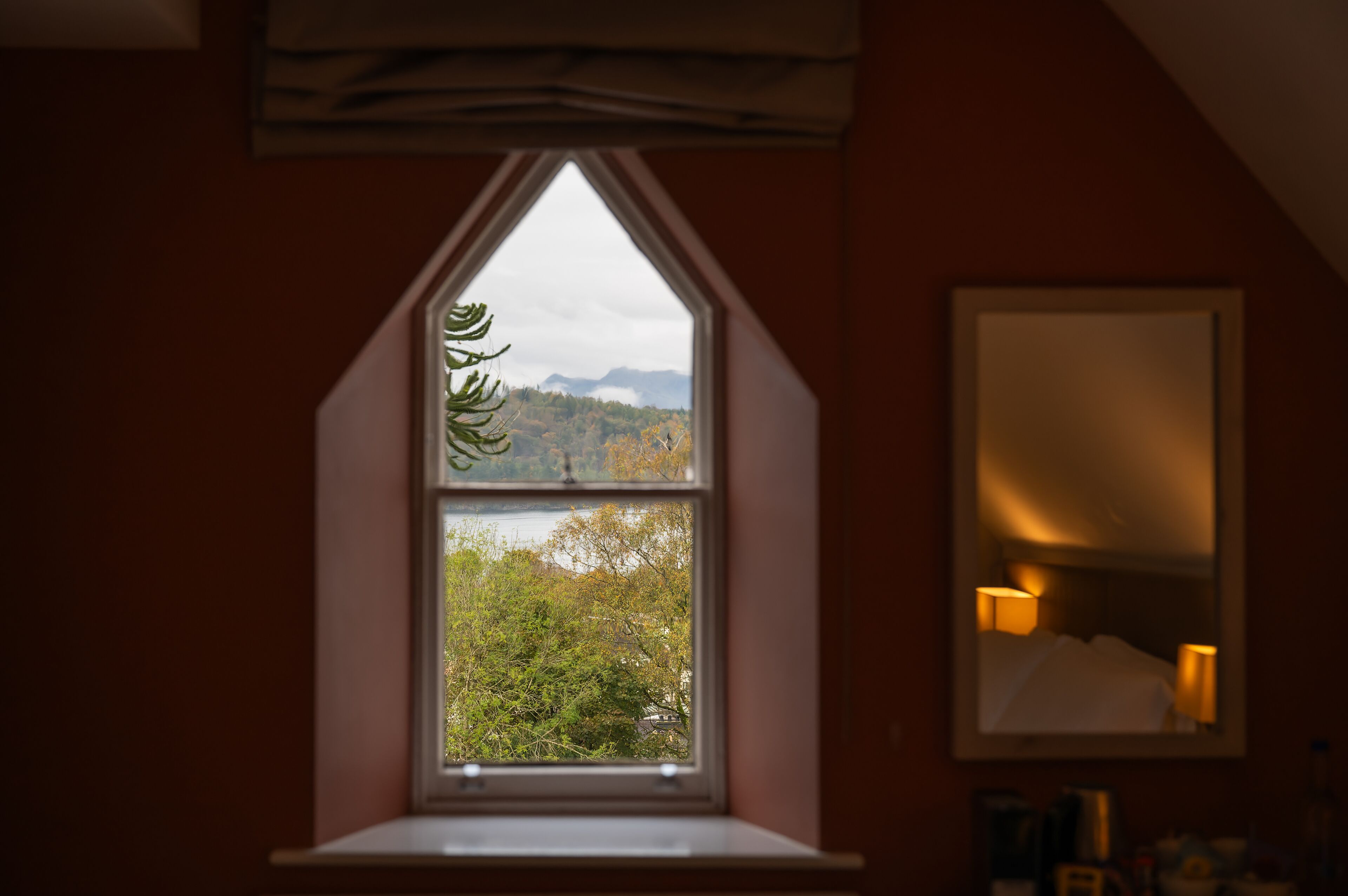 Ein Zimmer mit Fensterblick auf bewaldetes Gebiet und Berge.