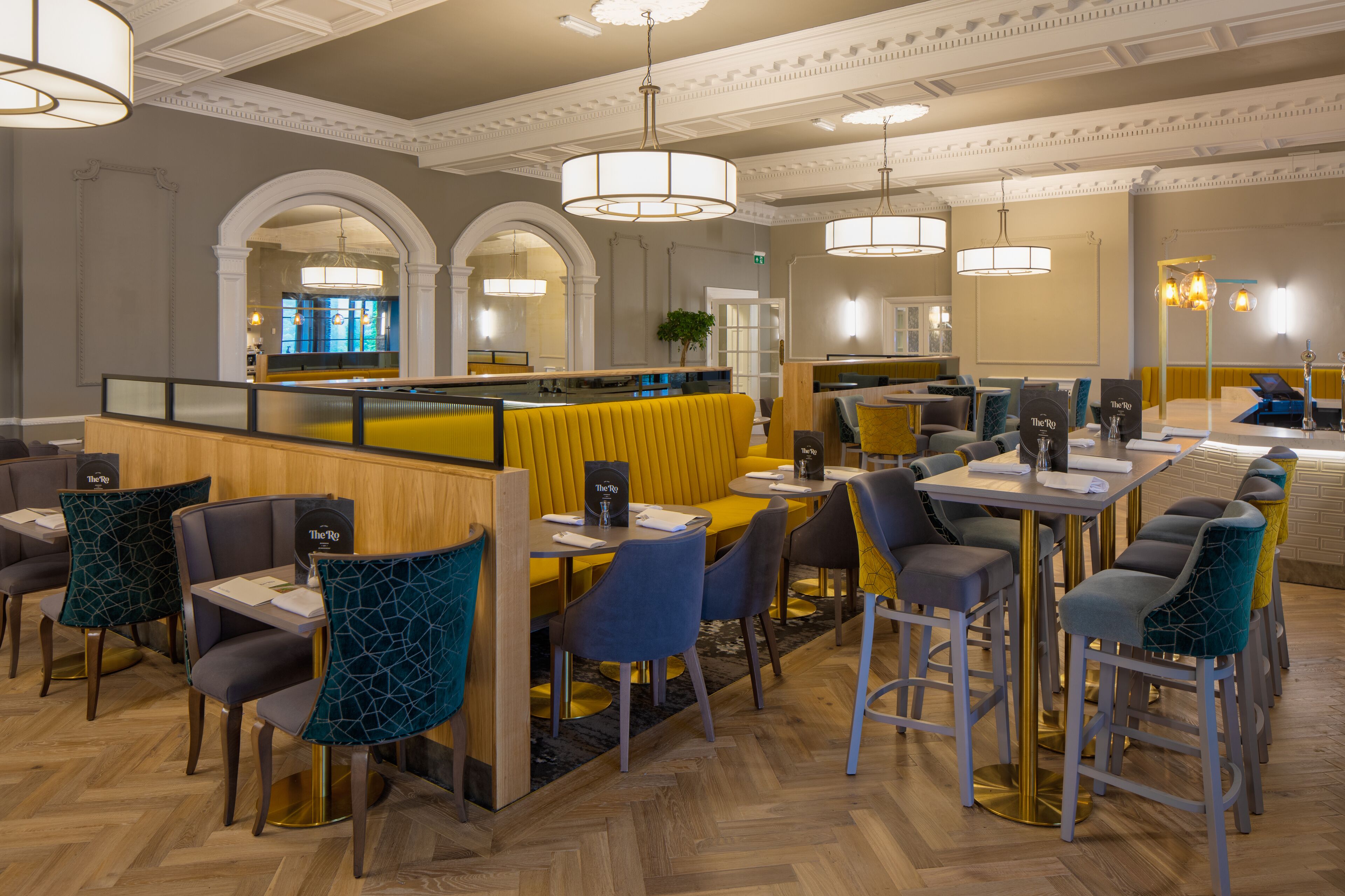 A restaurant with booths and tables, wooden flooring, and modern lighting fixtures.