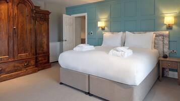 A bedroom with a large bed, a wardrobe, and two wall-mounted lamps.