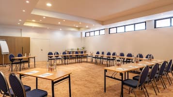 Un salón de conferencias con una mesa larga, sillas, una pizarra y suelo alfombrado.