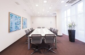A conference room with a long table, chairs, and two abstract paintings on the wall. - Estrel Hotel Berlin (Berlin)
